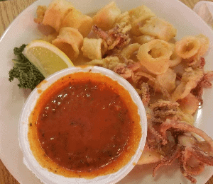 Anillos y tentáculos de calamar ligeramente fritos, servidos con salsa marinara.